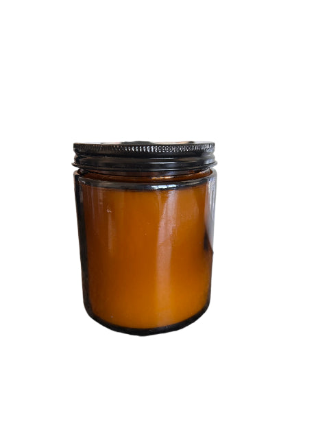 Brown jar with black lid on a textured surface next to a white frame with photos